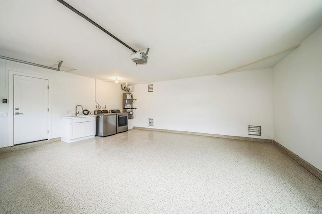 garage with a sink, independent washer and dryer, and a garage door opener