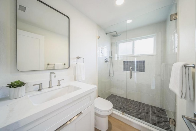 full bath with vanity, visible vents, a stall shower, and toilet