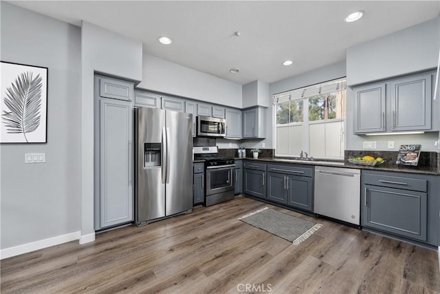 kitchen with dark wood-type flooring, dark countertops, appliances with stainless steel finishes, and gray cabinetry