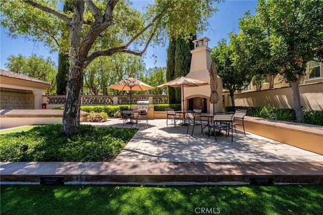 view of patio featuring exterior fireplace, fence, and outdoor dining space