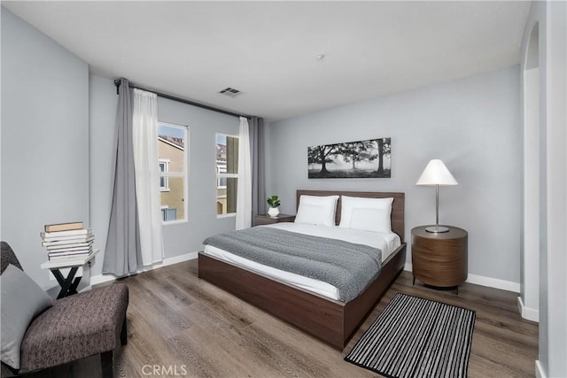 bedroom with wood finished floors, visible vents, and baseboards