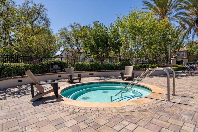 view of swimming pool with fence and a hot tub