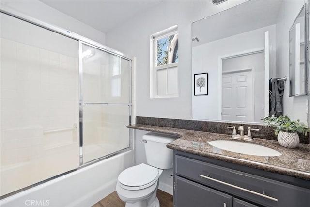 bathroom featuring wood finished floors, toilet, vanity, and bath / shower combo with glass door
