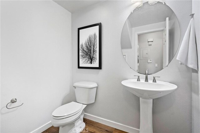 bathroom with wood finished floors, toilet, and baseboards