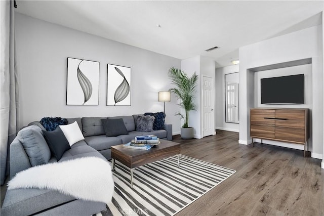 living area featuring baseboards, wood finished floors, and visible vents
