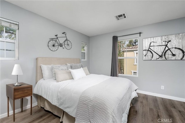 bedroom featuring wood finished floors, visible vents, and baseboards