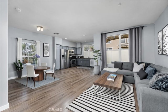 living room featuring light wood-type flooring, baseboards, and visible vents
