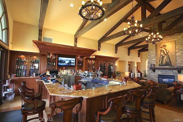 2019 Via Mariposa W Unit G, Laguna Woods, CA 92637 - indoor bar featuring a chandelier, high vaulted ceiling, beamed ceiling, a stone fireplace, and decorative light fixtures