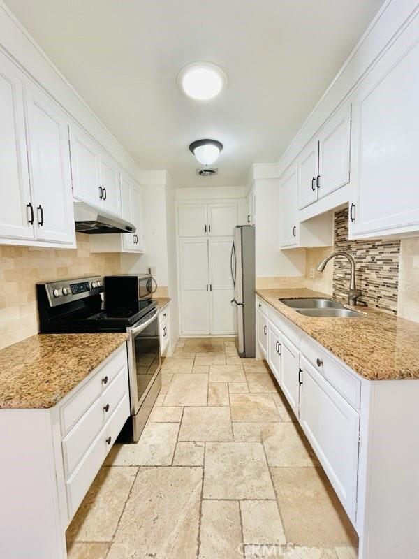 2019 Via Mariposa W Unit G, Laguna Woods, CA 92637 - kitchen featuring stainless steel appliances, a sink, under cabinet range hood, stone tile flooring, and white cabinets