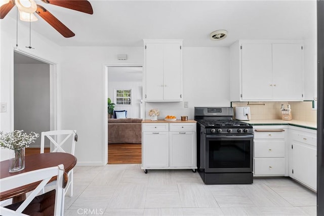 kitchen with light countertops, stainless steel gas range, a ceiling fan, white cabinetry, and backsplash