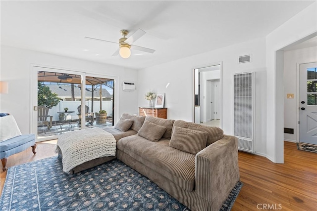 living area featuring a healthy amount of sunlight, visible vents, a heating unit, and ceiling fan