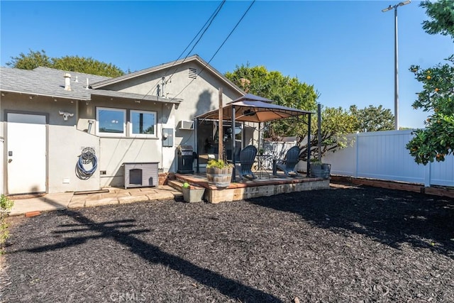 rear view of house with a patio, a gazebo, stucco siding, and fence