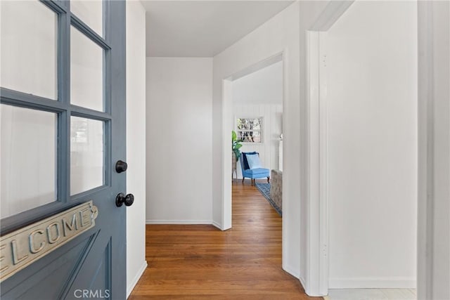 hallway featuring light wood-style flooring and baseboards
