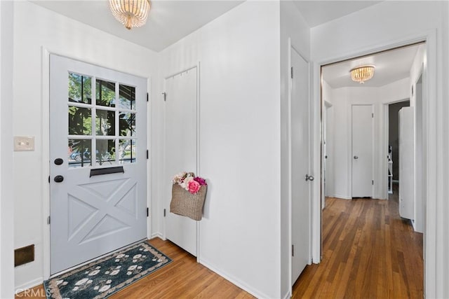 doorway featuring wood finished floors and an inviting chandelier