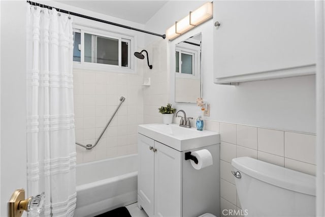 full bath with toilet, shower / tub combo, vanity, and tile walls