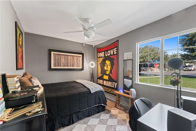 bedroom featuring ceiling fan, multiple windows, and wood finished floors