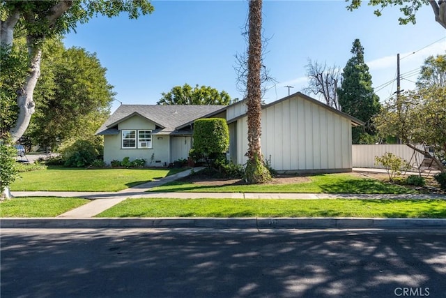ranch-style home featuring a front yard, fence, and board and batten siding