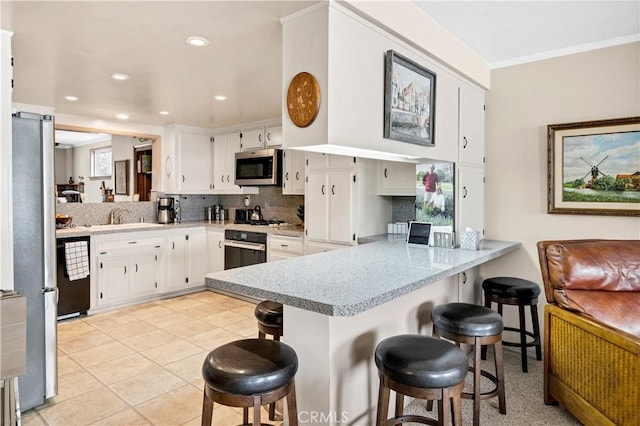 250 N Wateka St, San Jacinto, CA 92583 - kitchen featuring appliances with stainless steel finishes, a peninsula, a kitchen bar, decorative backsplash, and crown molding