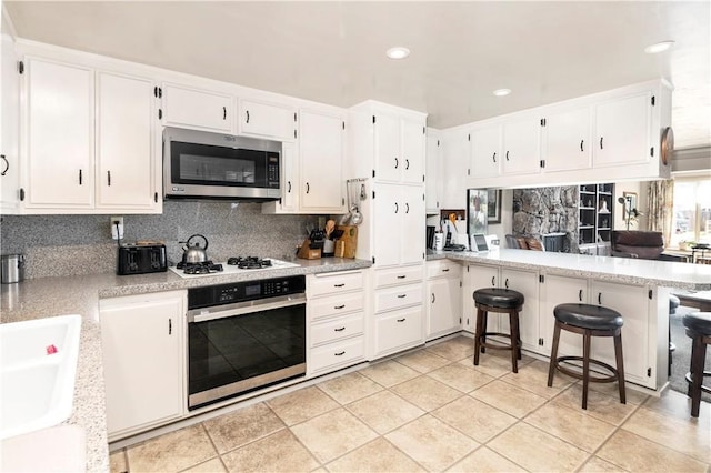 250 N Wateka St, San Jacinto, CA 92583 - kitchen with appliances with stainless steel finishes, backsplash, a peninsula, recessed lighting, and light countertops