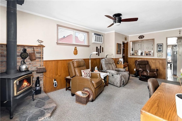 250 N Wateka St, San Jacinto, CA 92583 - carpeted living area with wainscoting, a wood stove, wooden walls, ceiling fan, and crown molding