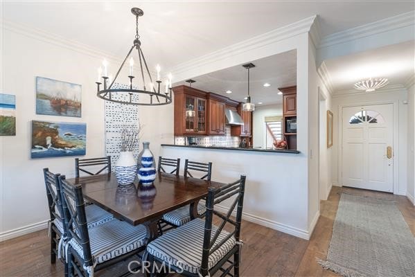 dining room featuring crown molding, baseboards, a notable chandelier, and wood finished floors