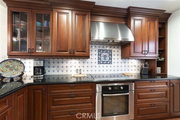 kitchen featuring decorative backsplash, wall chimney range hood, black electric cooktop, and stainless steel oven