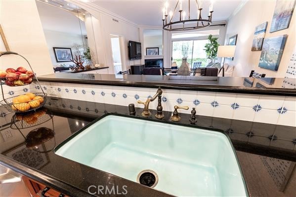 interior space with a sink, ornamental molding, and dark countertops
