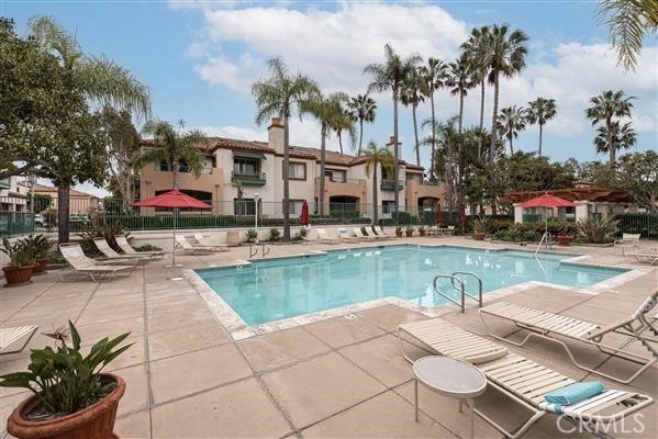 pool with a patio area, fence, and a residential view