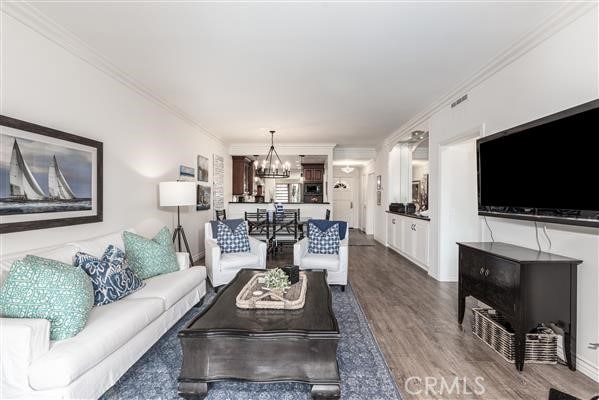 living room featuring a notable chandelier, crown molding, and wood finished floors