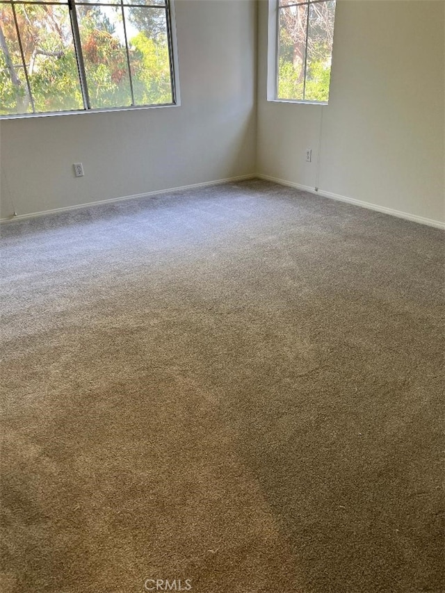 spare room featuring carpet flooring and baseboards