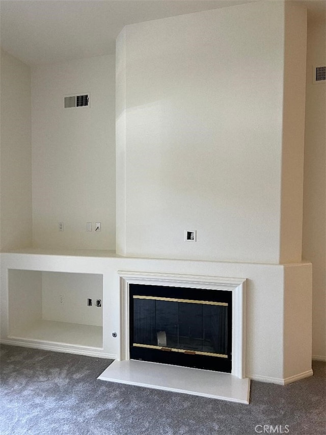 room details featuring visible vents, carpet floors, and a glass covered fireplace