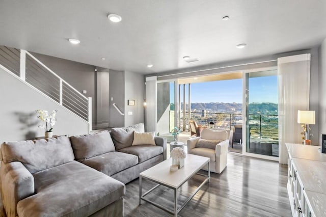 living area featuring stairway, wood finished floors, a wall of windows, a mountain view, and recessed lighting