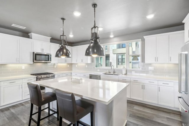 kitchen with dark wood finished floors, backsplash, stainless steel appliances, and a sink