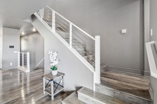 stairway with baseboards and wood finished floors