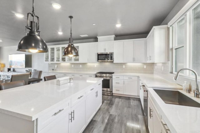 kitchen with white cabinets, wood finished floors, a sink, and appliances with stainless steel finishes