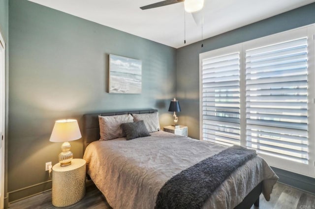 bedroom featuring baseboards, multiple windows, and wood finished floors
