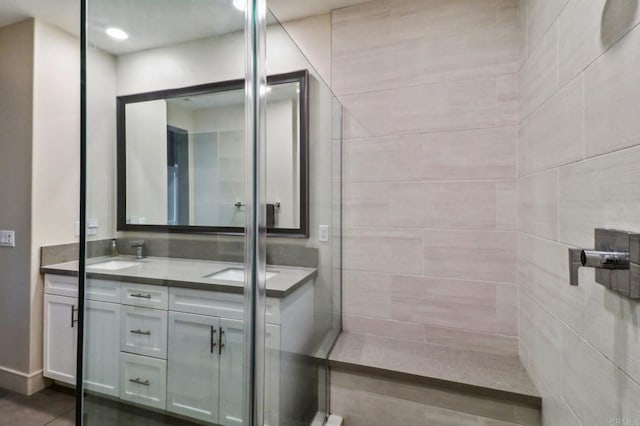 bathroom featuring a sink, double vanity, and tiled shower