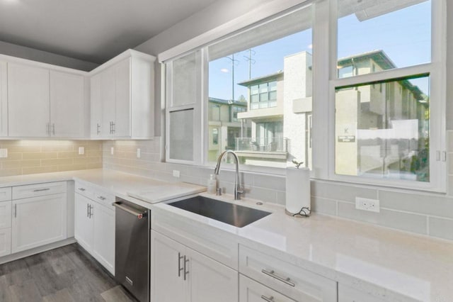kitchen featuring white cabinets, decorative backsplash, dishwasher, and a sink
