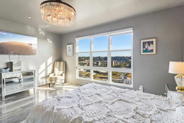 bedroom featuring baseboards, wood finished floors, and an inviting chandelier