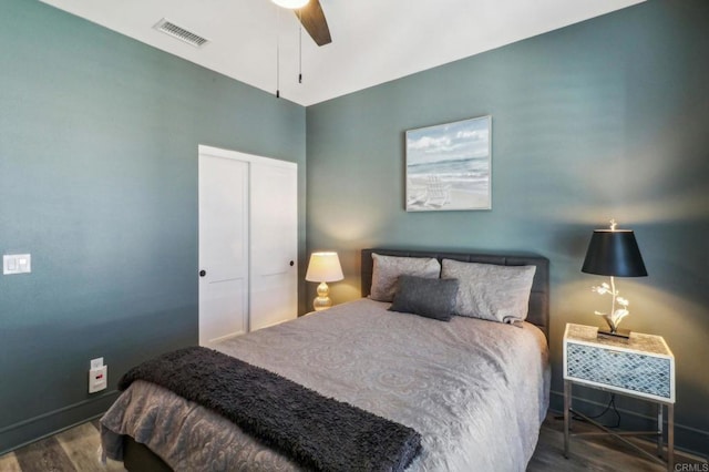 bedroom with wood finished floors, a closet, ceiling fan, baseboards, and visible vents