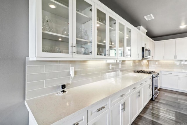 kitchen featuring white cabinets, stainless steel appliances, visible vents, and backsplash