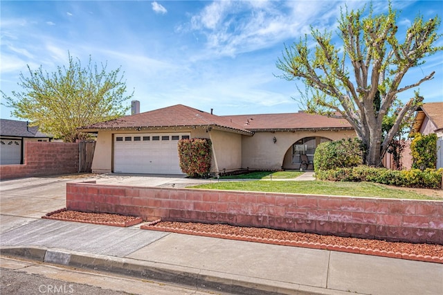 view of front of house with an attached garage, driveway, stucco siding, and fence