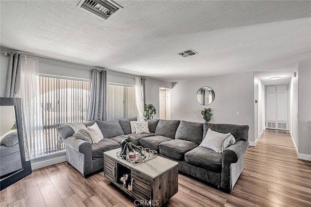 living area with visible vents, a textured ceiling, and wood finished floors