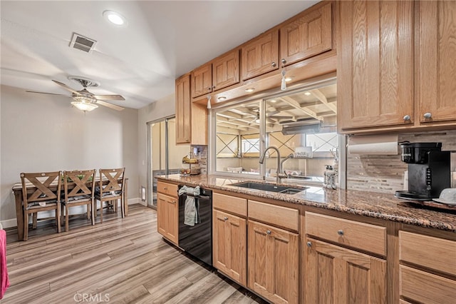 kitchen featuring tasteful backsplash, visible vents, black dishwasher, a sink, and light wood-style flooring