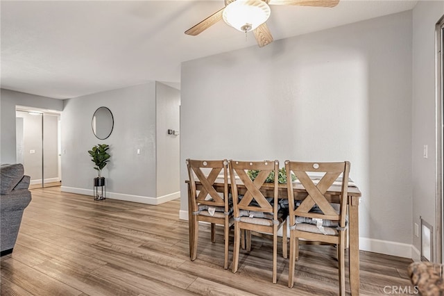 dining room with light wood-type flooring, baseboards, and a ceiling fan