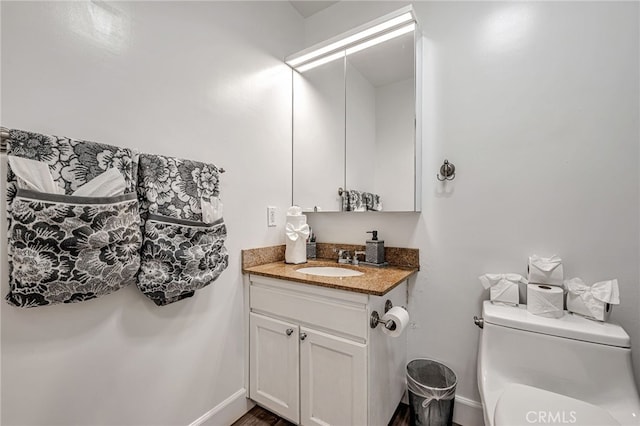 bathroom featuring toilet, vanity, and baseboards