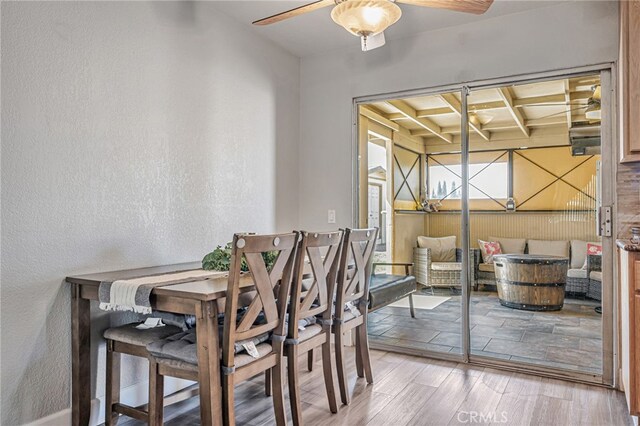 dining room with a textured wall, a ceiling fan, beamed ceiling, coffered ceiling, and wood finished floors