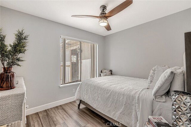 bedroom with wood finished floors, baseboards, and a ceiling fan