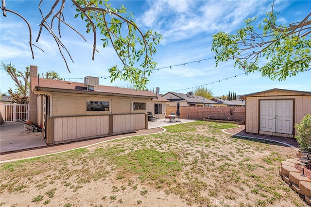 view of yard featuring a patio area, a fenced backyard, a storage unit, and an outdoor structure
