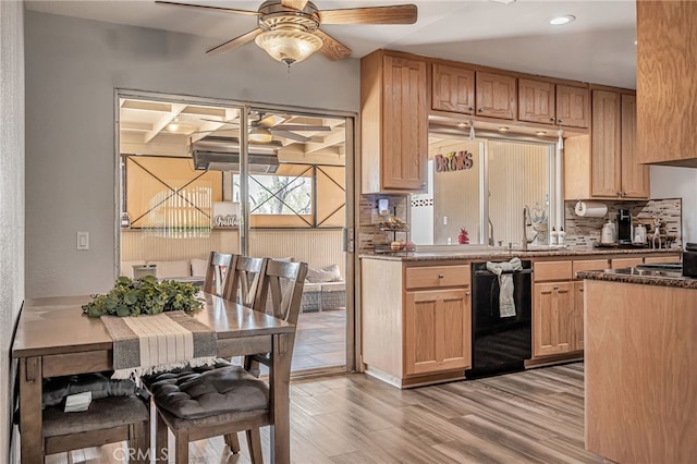 kitchen featuring tasteful backsplash, a ceiling fan, black dishwasher, a sink, and light wood finished floors